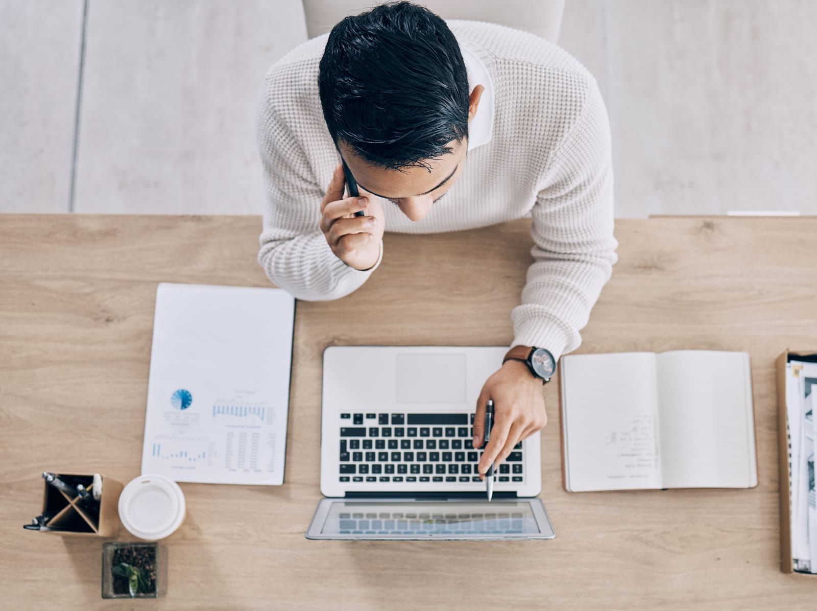 man working on his laptop while taking a call